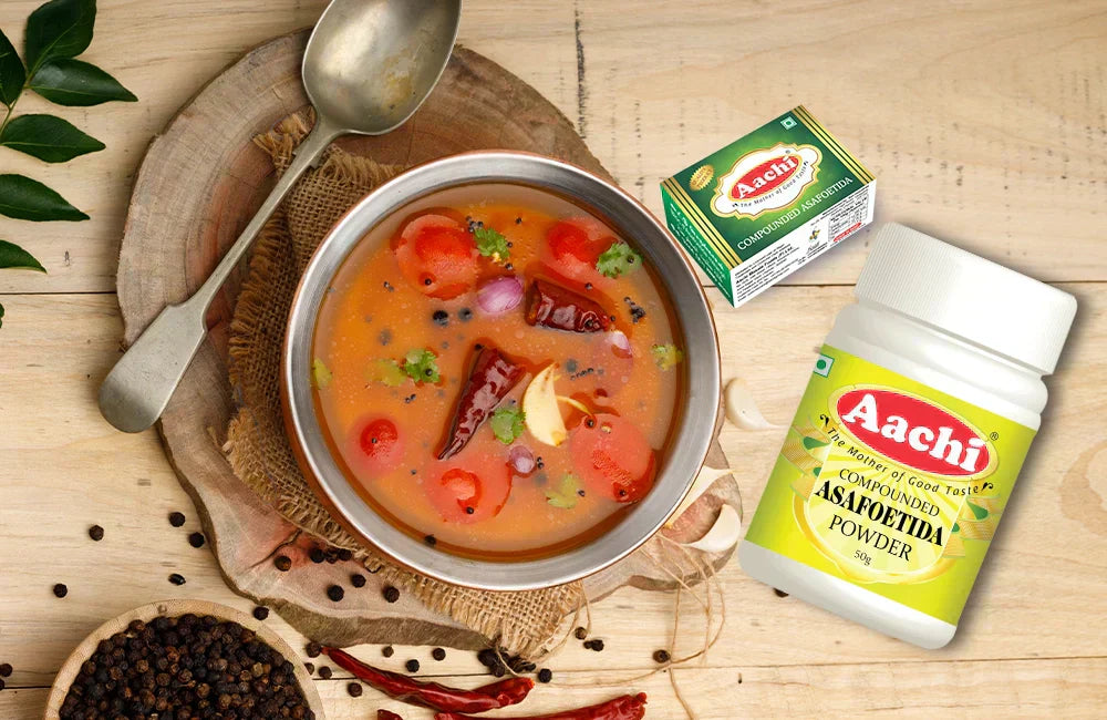 Aachi Asafoetida Powder blended into aromatic rasam with visible garlic, red chilies, and black pepper.