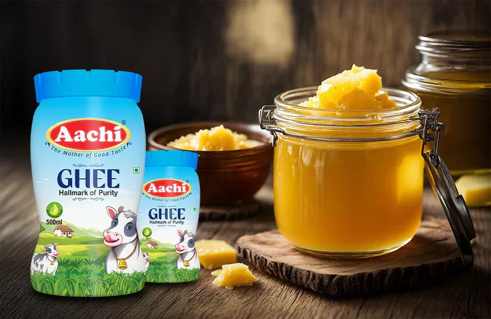 Aachi Ghee packs placed beside a glass jar filled with golden ghee on a wooden surface.