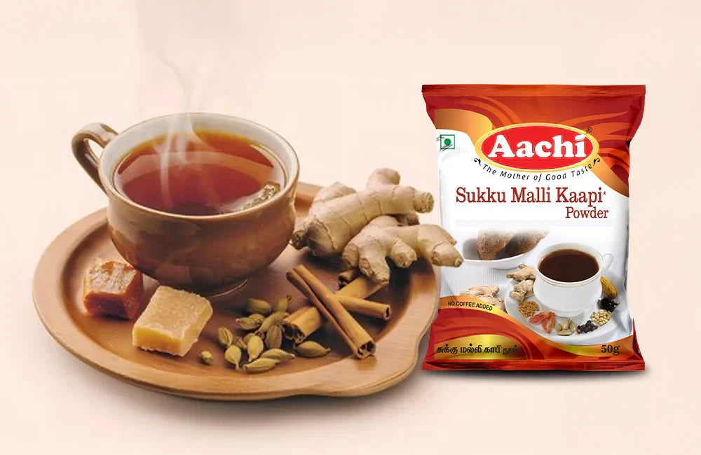 Sukku Malli Kaapi Powder with a steaming cup of herbal drink, ginger, cardamom, and jaggery on a wooden tray.