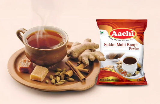 Sukku Malli Kaapi Powder with a steaming cup of herbal drink, ginger, cardamom, and jaggery on a wooden tray.